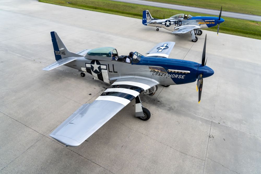 A restored P-51 Mustang warbird aircraft with silver and blue paint scheme on display.