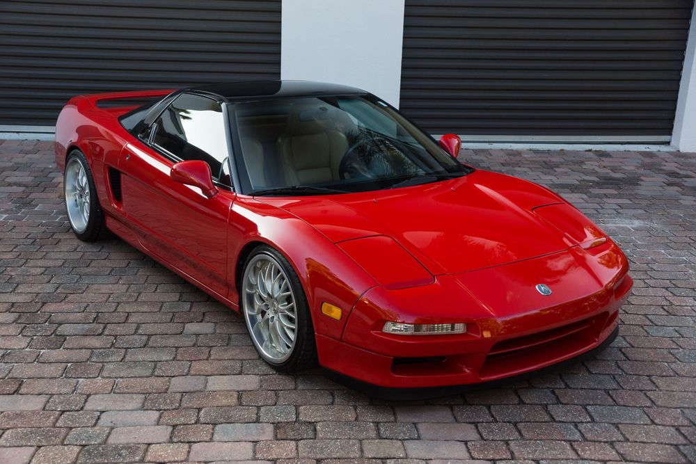 Red Acura NSX convertible with aftermarket wheels shown at three-quarter front angle.