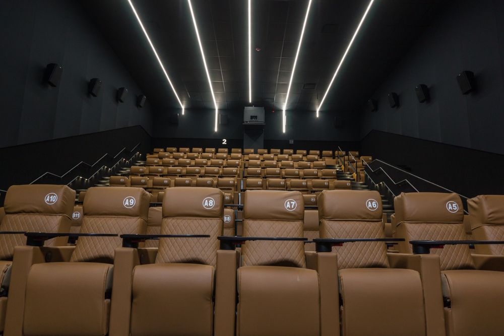Movie theater interior showing rows of brown leather seats with modern lighting design.