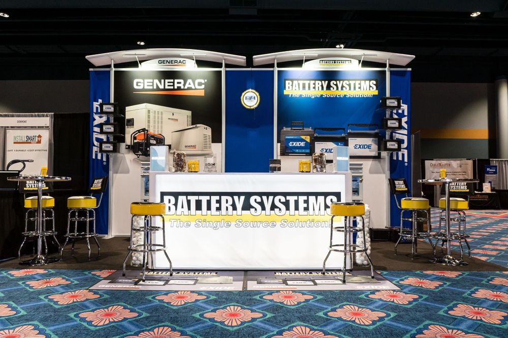 Generac and Battery Systems trade show booth with blue and white display panels and counter.