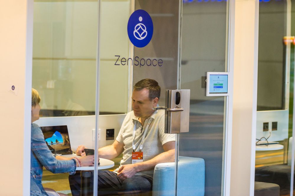 An office space with Zen Spaces branding on glass walls and modern furniture inside.
