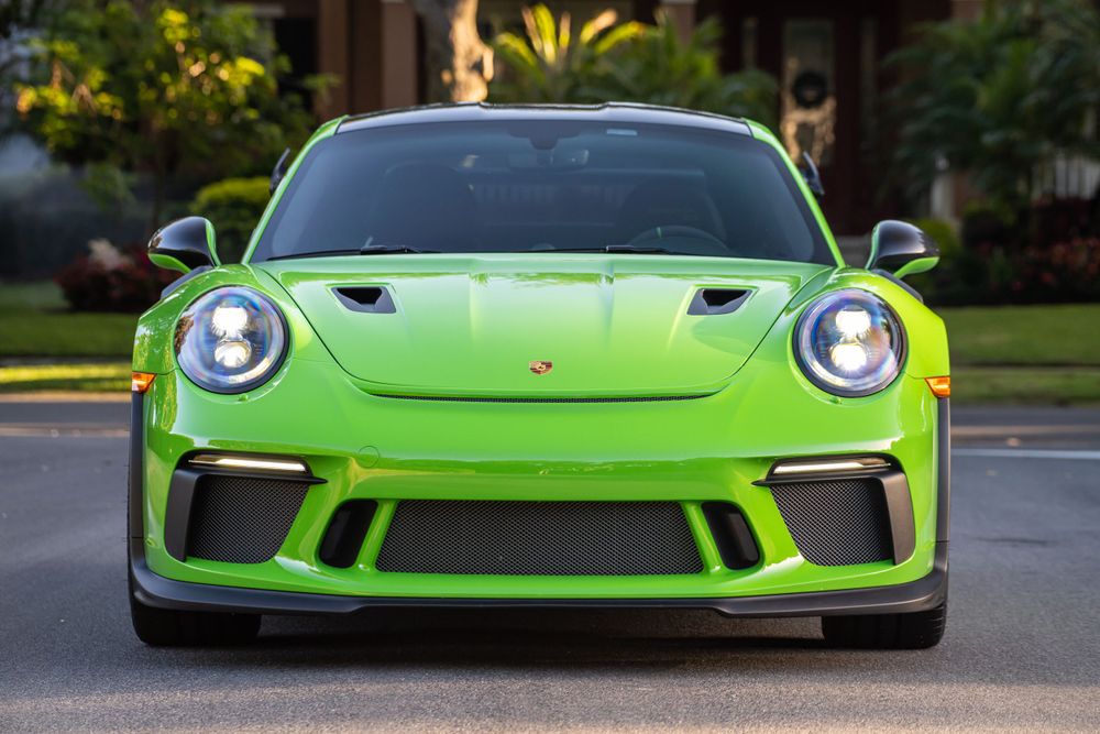 Bright lime green Porsche 911 GT3 front view showing distinctive LED headlights and aggressive front bumper.