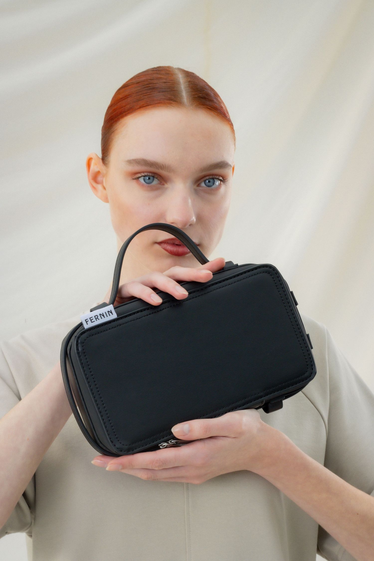 Modefotografie van vrouw met zwarte tas in haar handen, geschikt voor accessoires of modecampagnes.