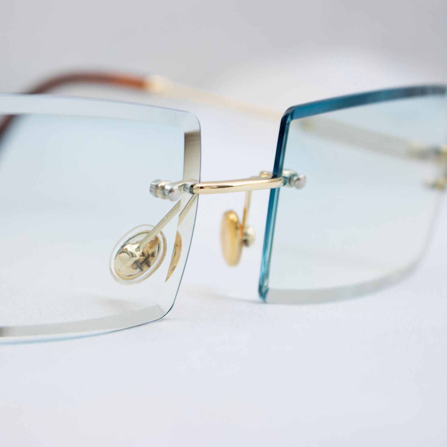 Close-up van een bril met gouden details en blauwe glazen, ideaal voor modeaccessoires en productfotografie.