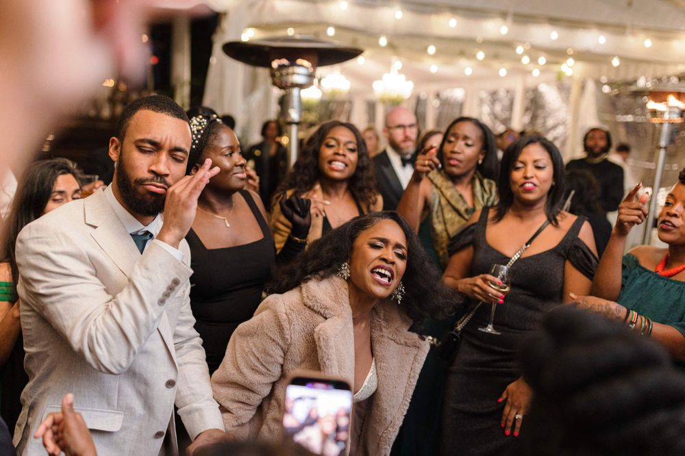 Wedding guests dancing and singing enthusiastically during a lively reception celebration.