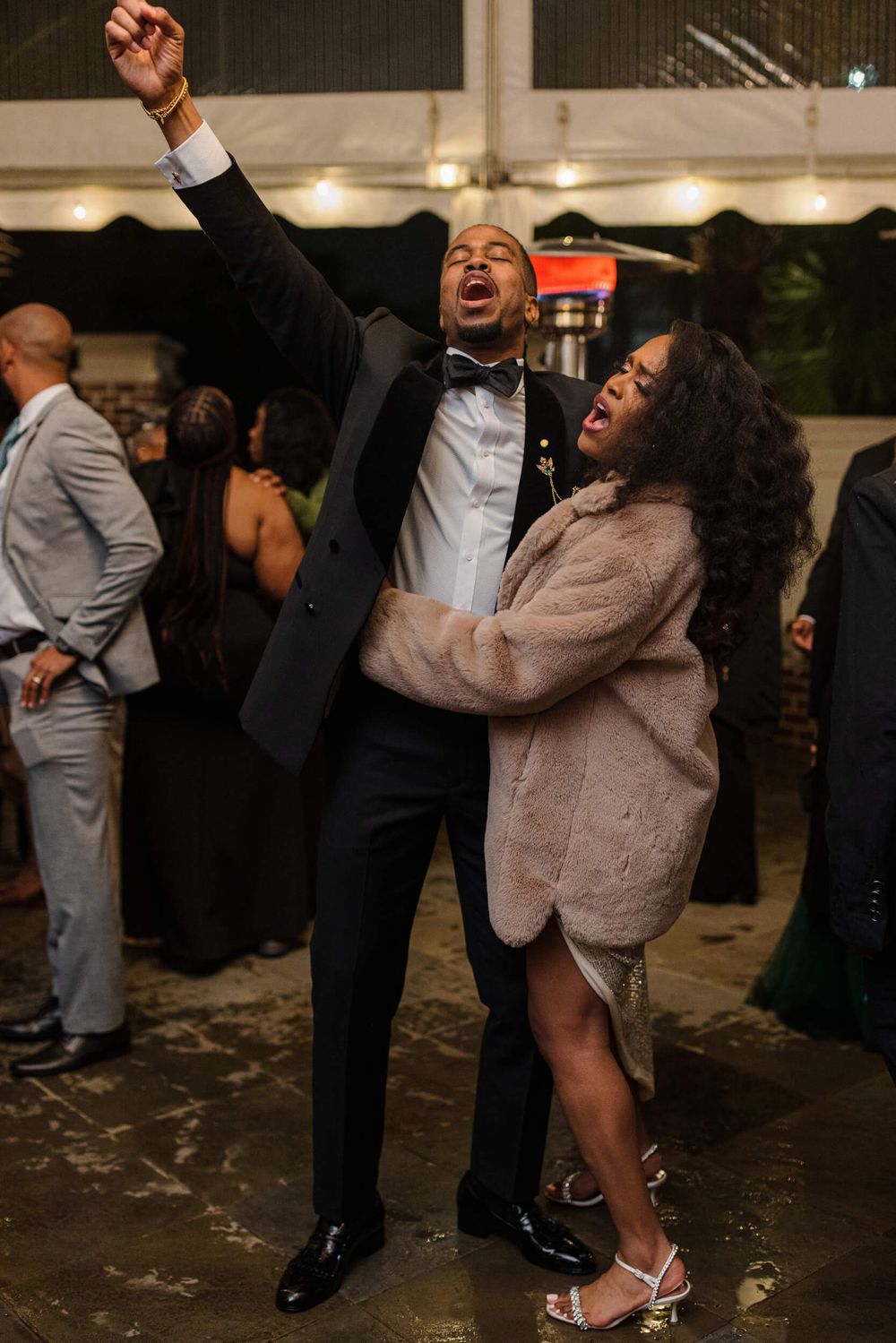 A couple dancing enthusiastically together at a wedding reception.