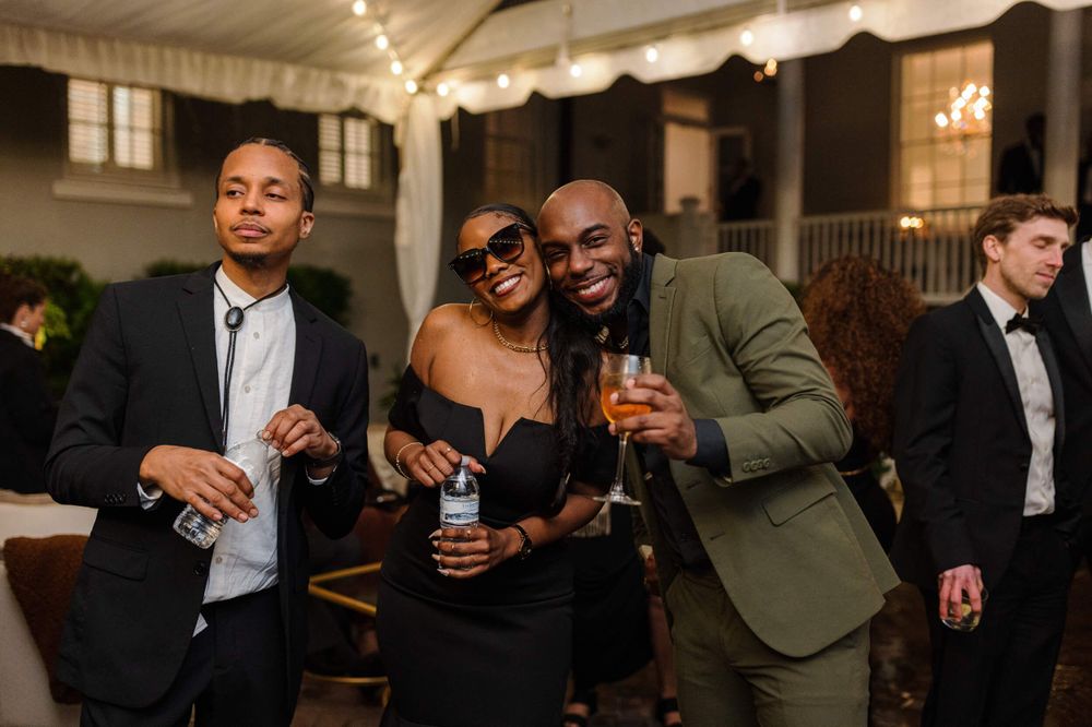Stylishly dressed guests enjoying drinks and conversation at an elegant indoor wedding reception.