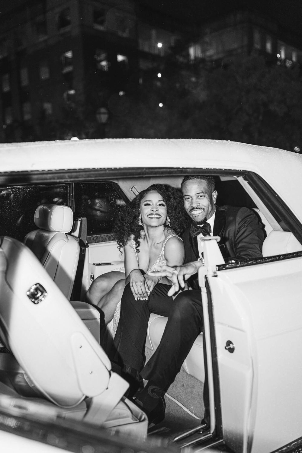 Happy couple sharing a moment in the backseat of a classic white car.