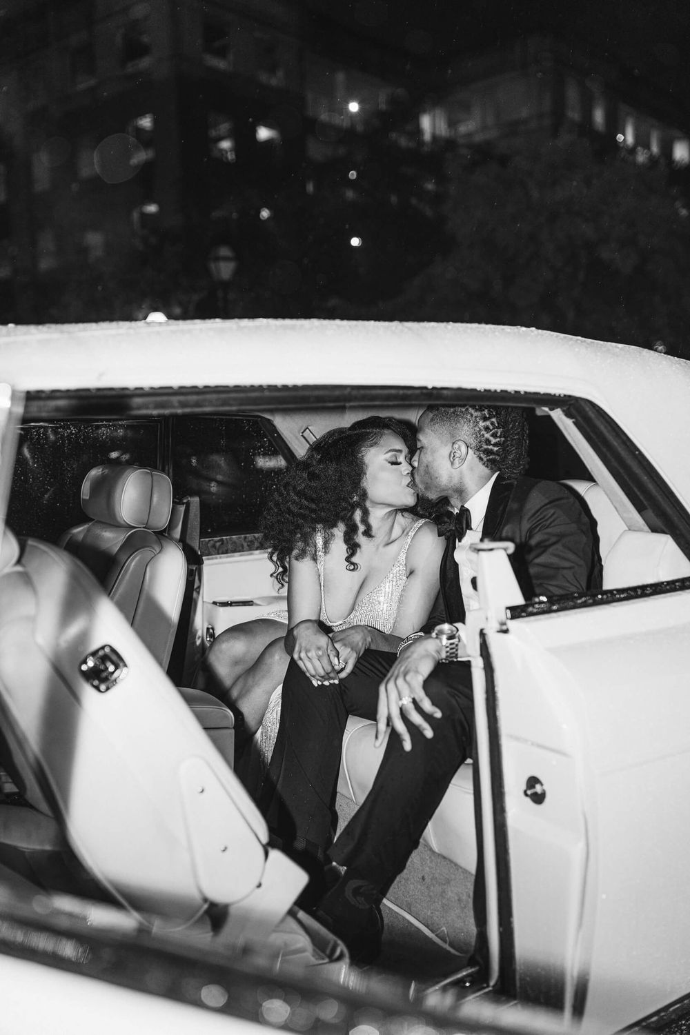 Intimate moment shared between couple in backseat of white car at night.