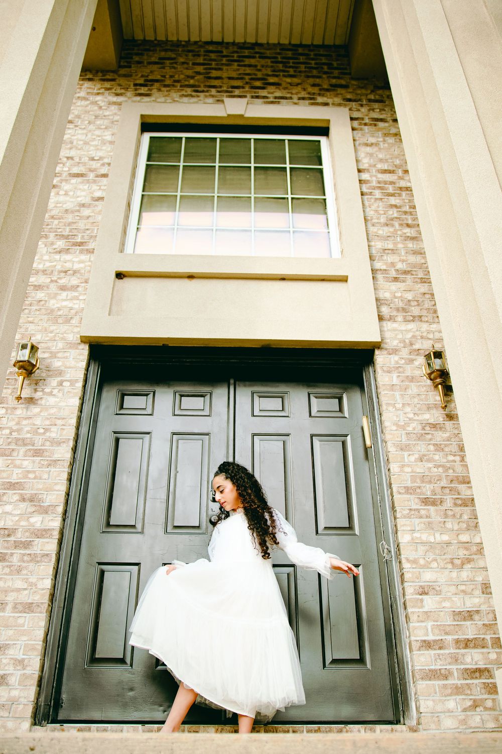 Beautiful classy bat mitzvah girl posing in front of her house for a professional photo.