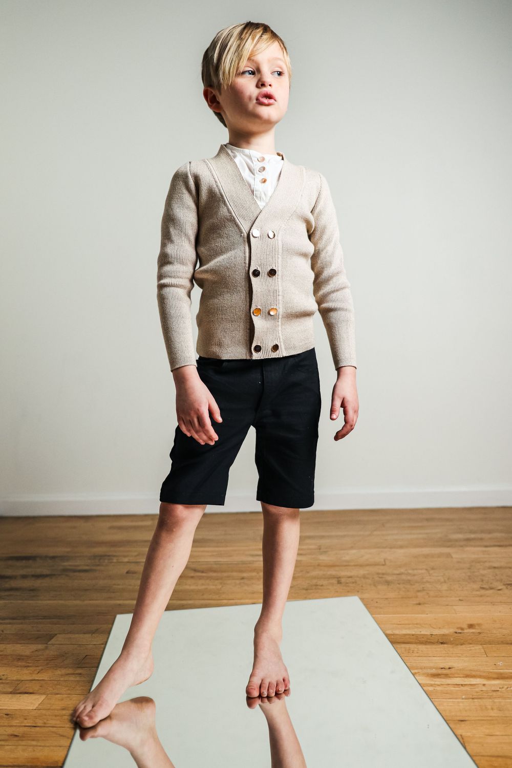 Stylized boy brand photoshoot. Model standing on mirror posing for a clothing store's website photography shoot.