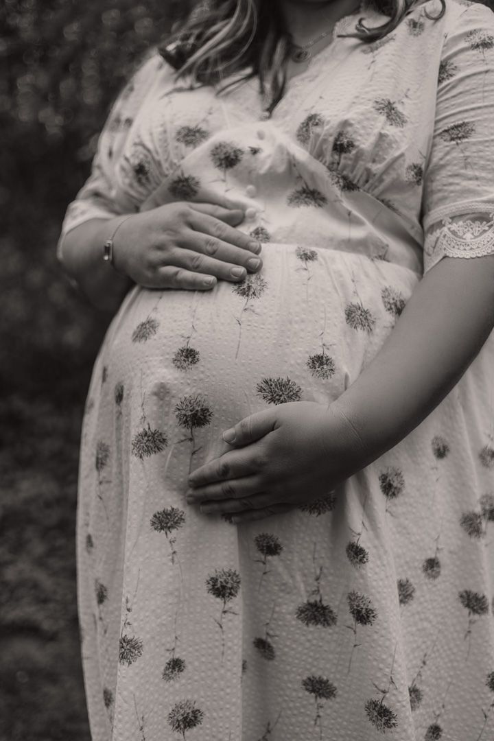 Black and white maternity photo of mum holding her belly