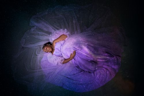 Ethereal overhead shot of woman in flowing purple gown creating circular pattern.