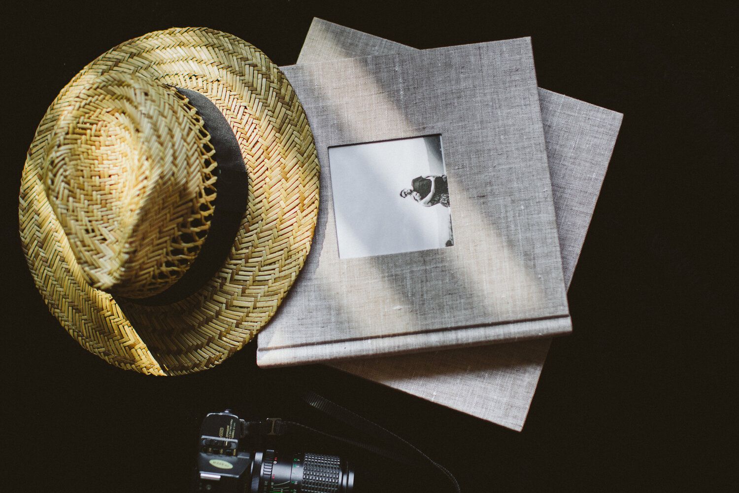 Straw hat and vintage photography equipment arranged with photo album pages.