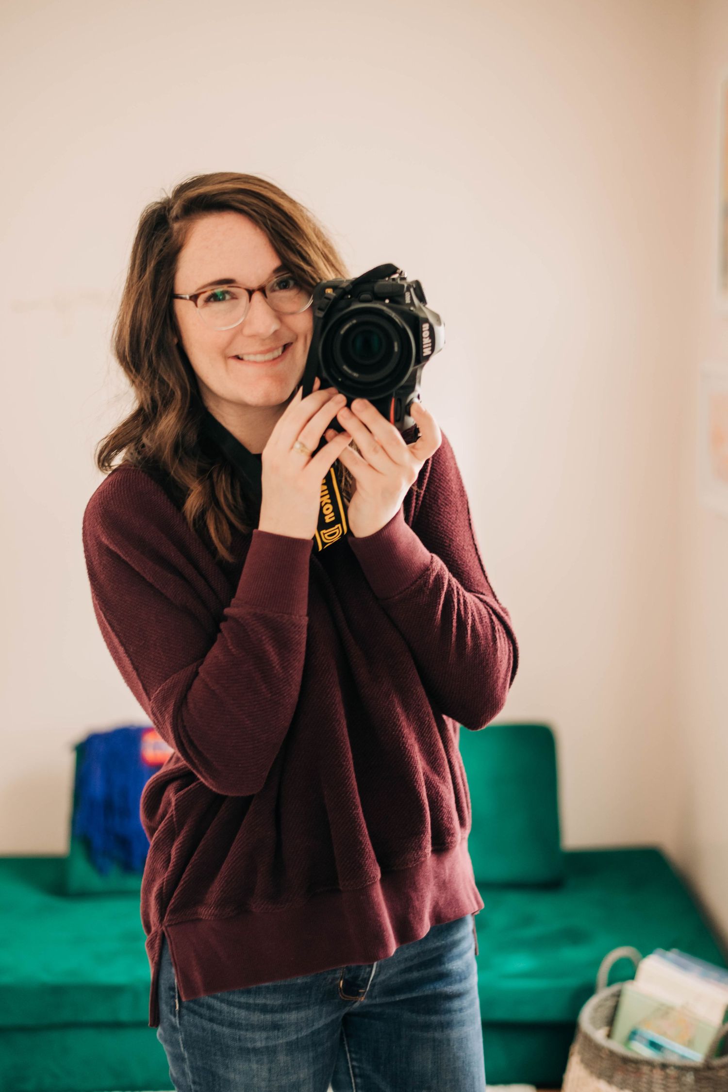 Woman wearing a maroon sweater and holding a camera