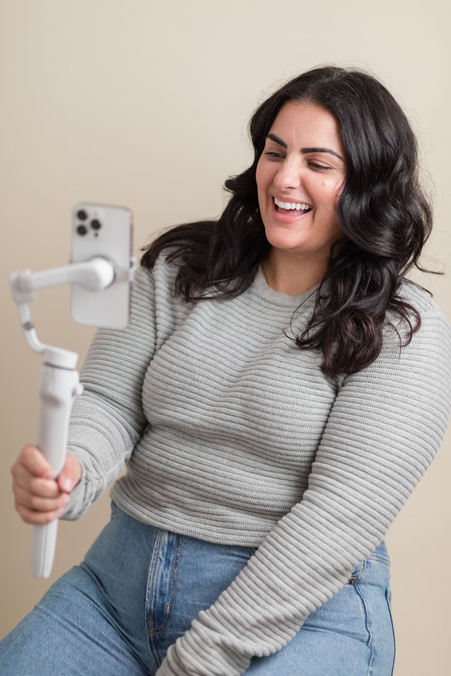 Content creator laughs while recording content with smartphone gimbal setup.