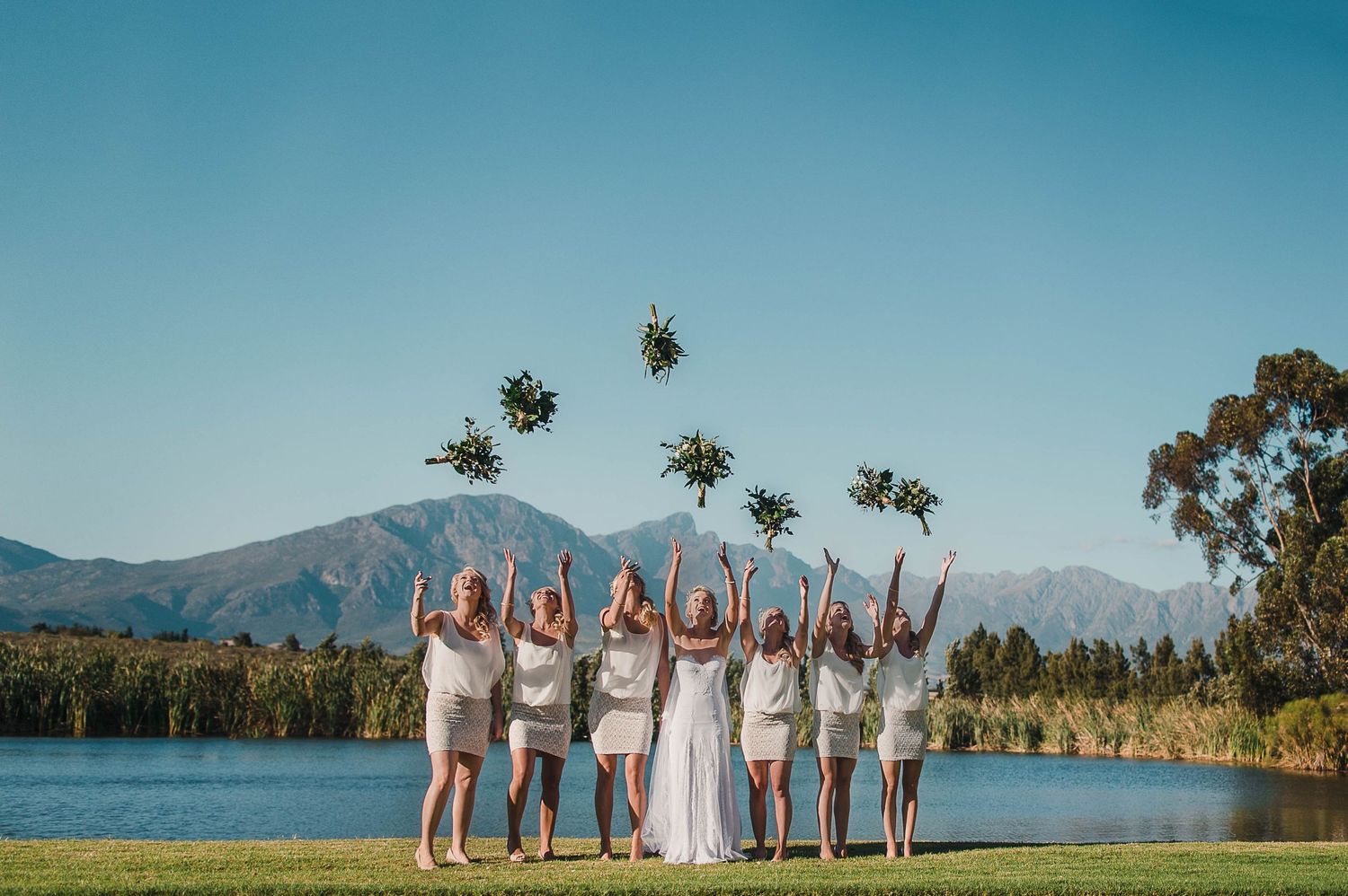 bride and bridesmaids tossing their bouquets in the air