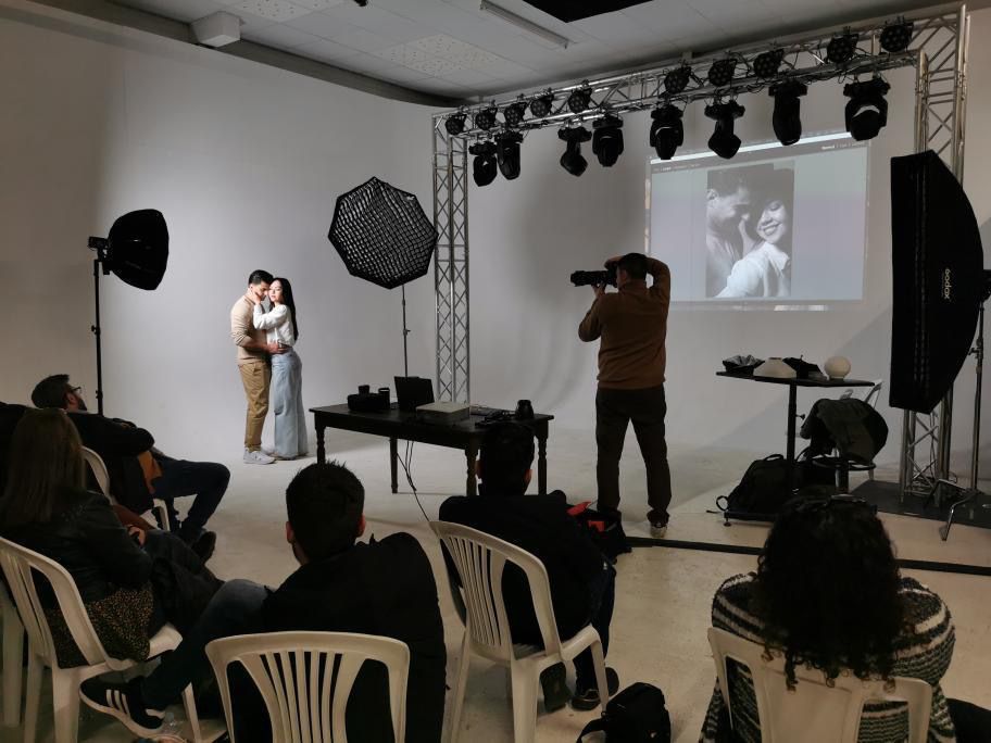 Dark indoor event space with lighting equipment and seated audience members.