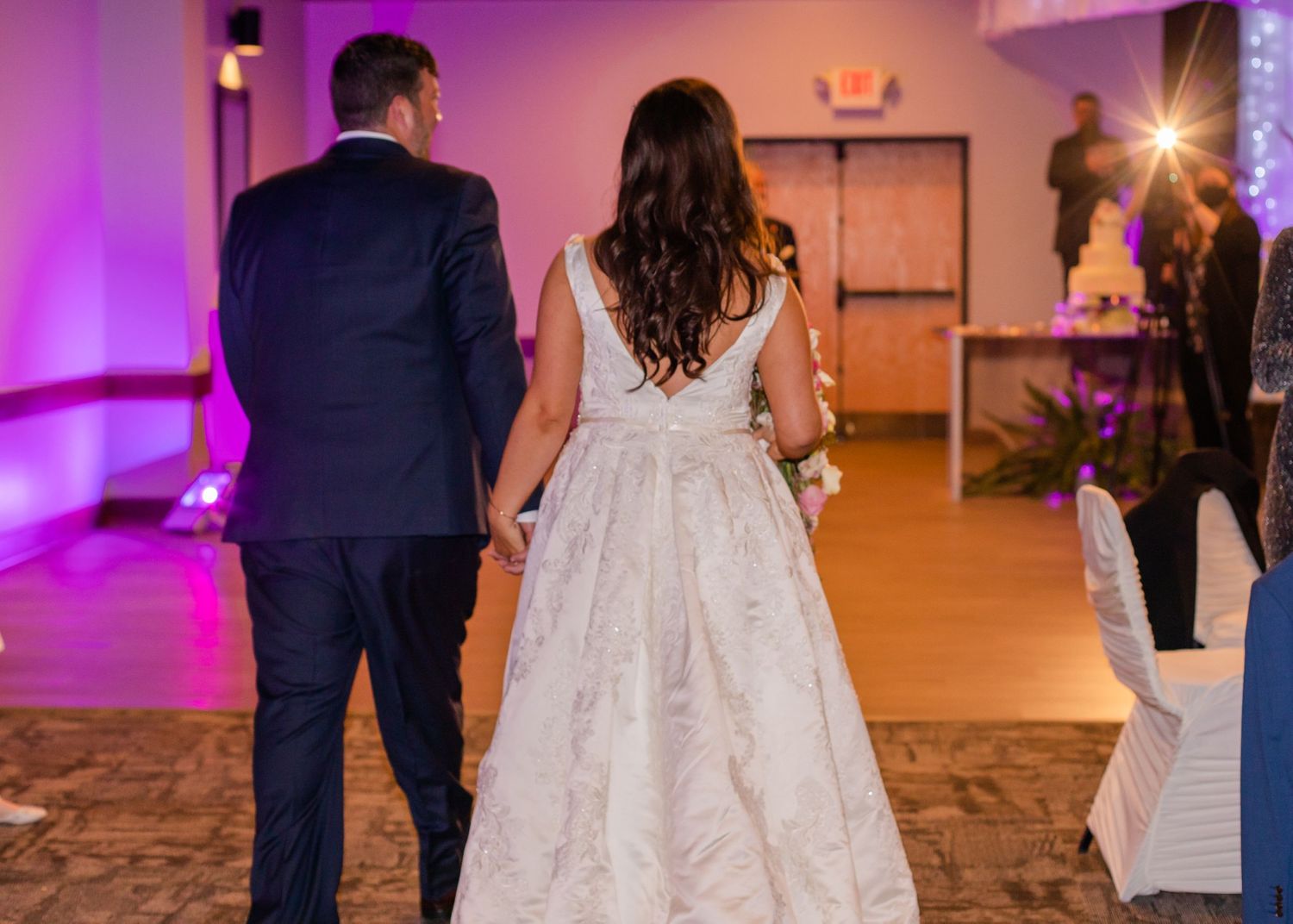 Wedding reception venue illuminated with purple lighting and elegant decor.