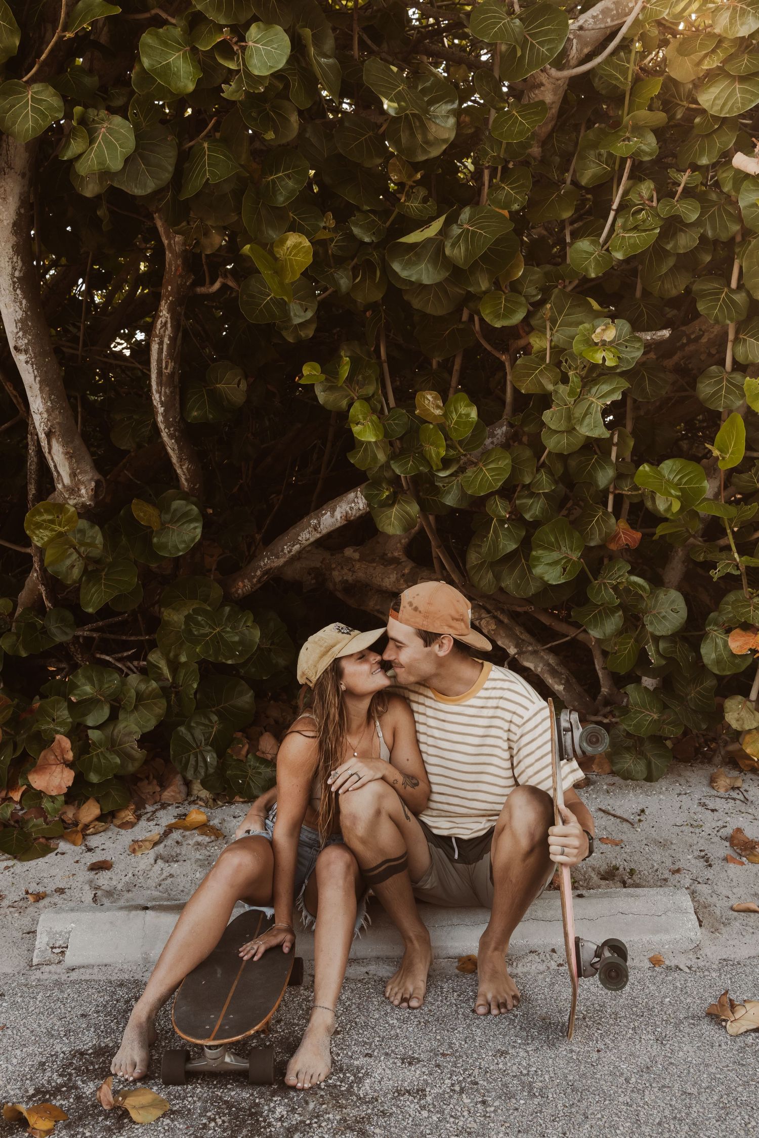 Skater couple kissing on the curb with their boards taken by South Florida Wedding Photographer Lemon and Honey Co.