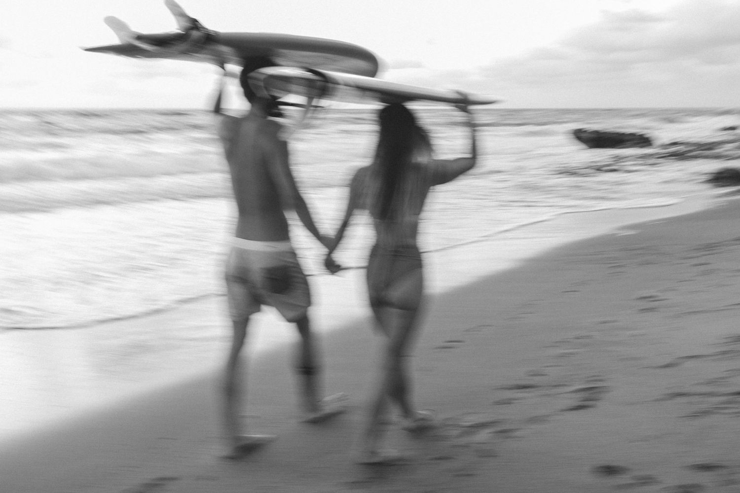 Surfer couple walking the beach taken by South Florida Wedding Photographer Lemon and Honey Co.