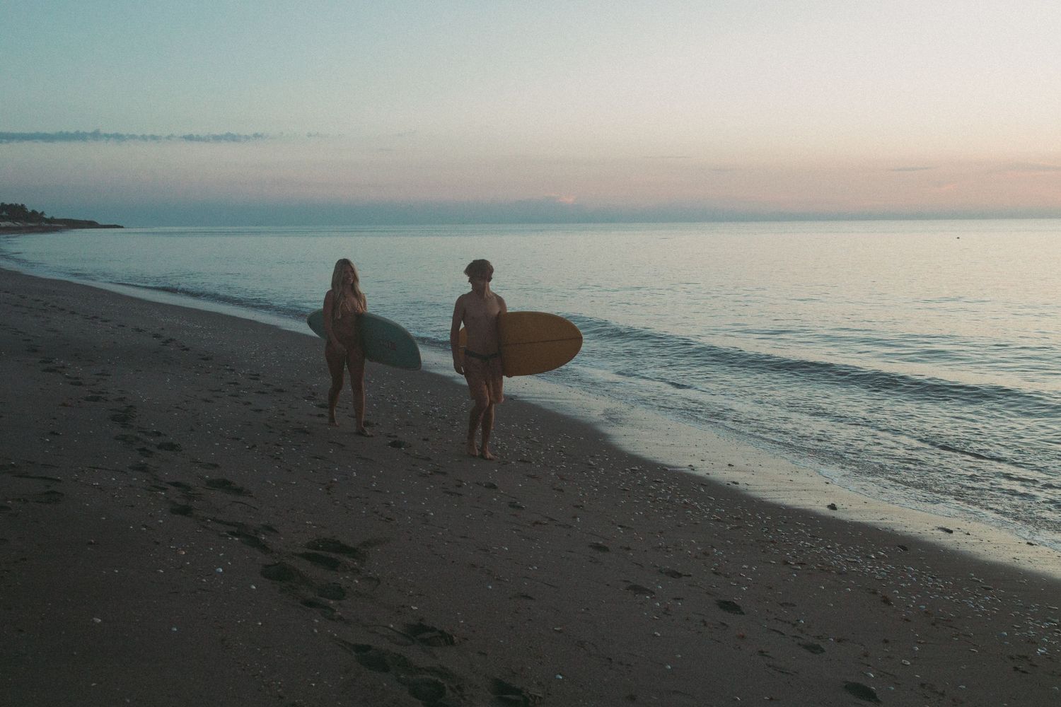 Surfer couple walking during blue hour on the beach taken by South Florida Wedding Photographer Lemon and Honey Co.