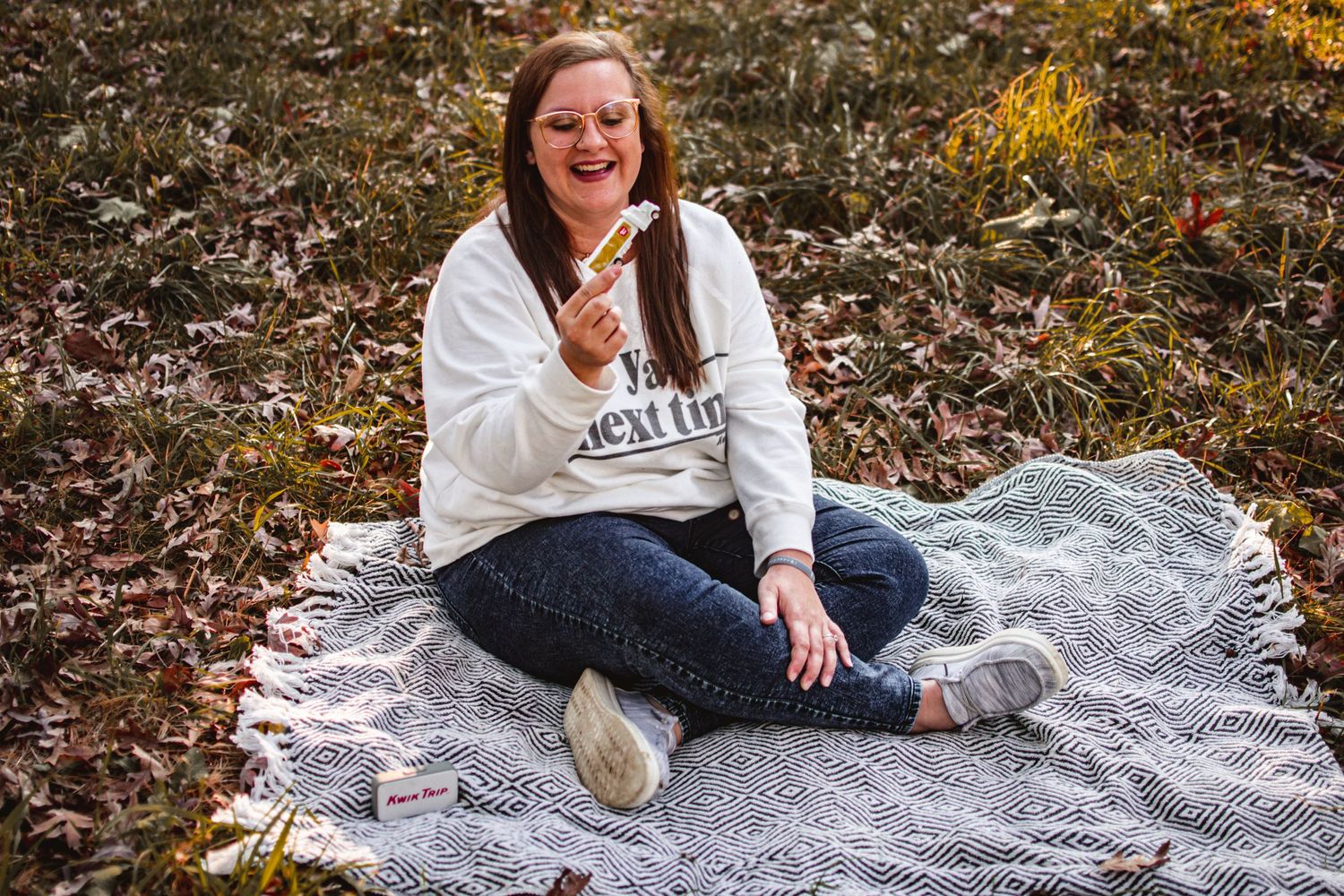 A candid autumn portrait on a blanket surrounded by fallen leaves.