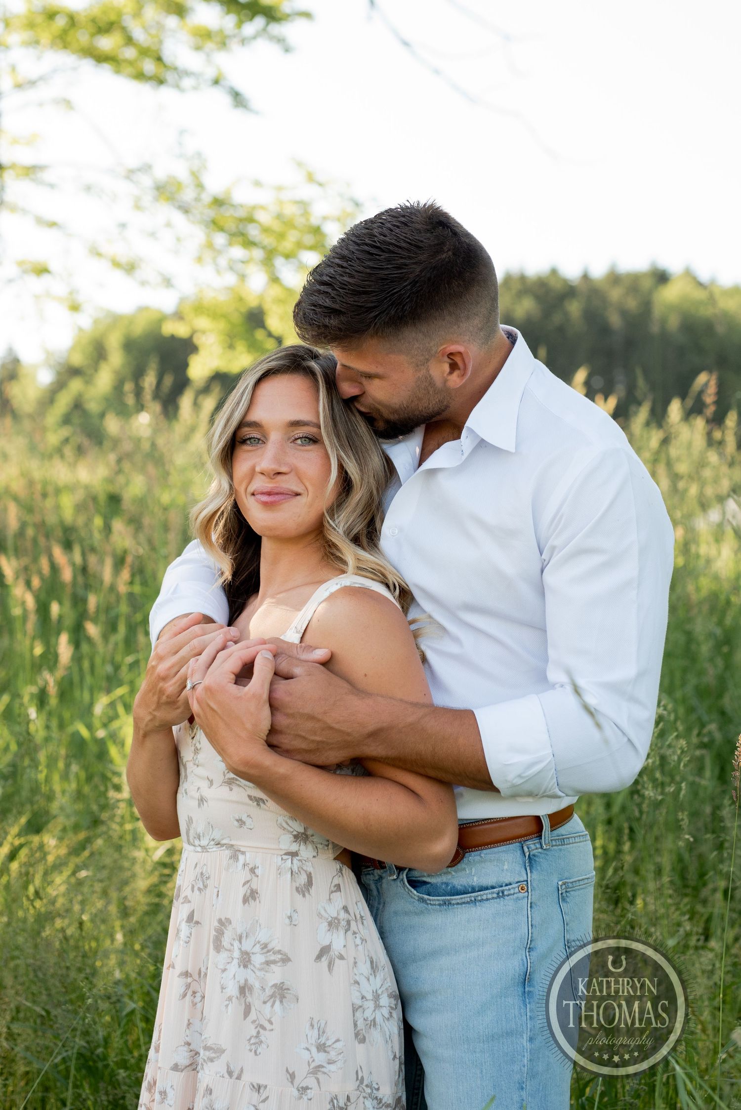 A tender moment between a couple embracing in a sunlit meadow with wildflowers.