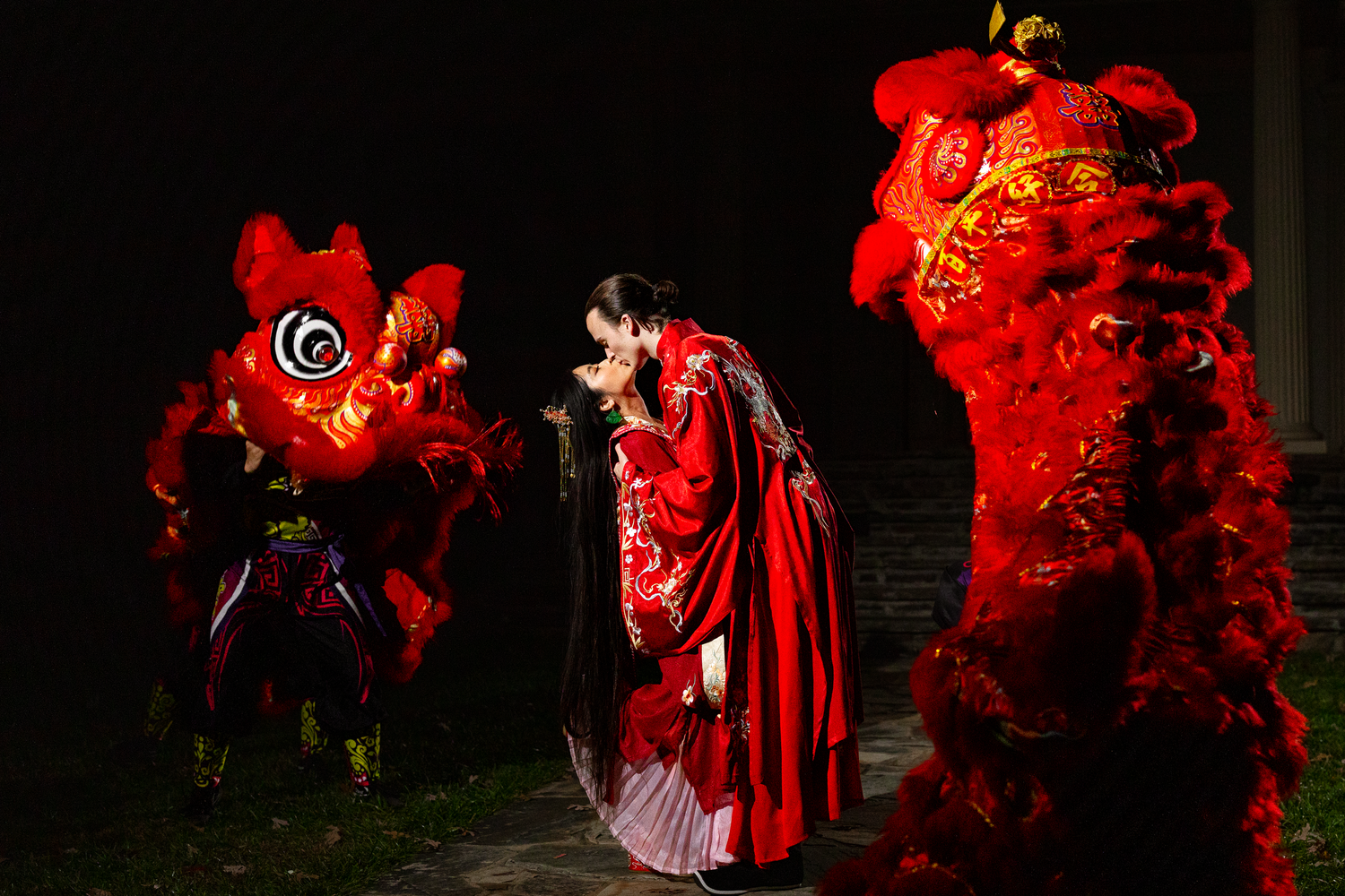 Traditional Asian wedding couple with red lion dance performers at night.