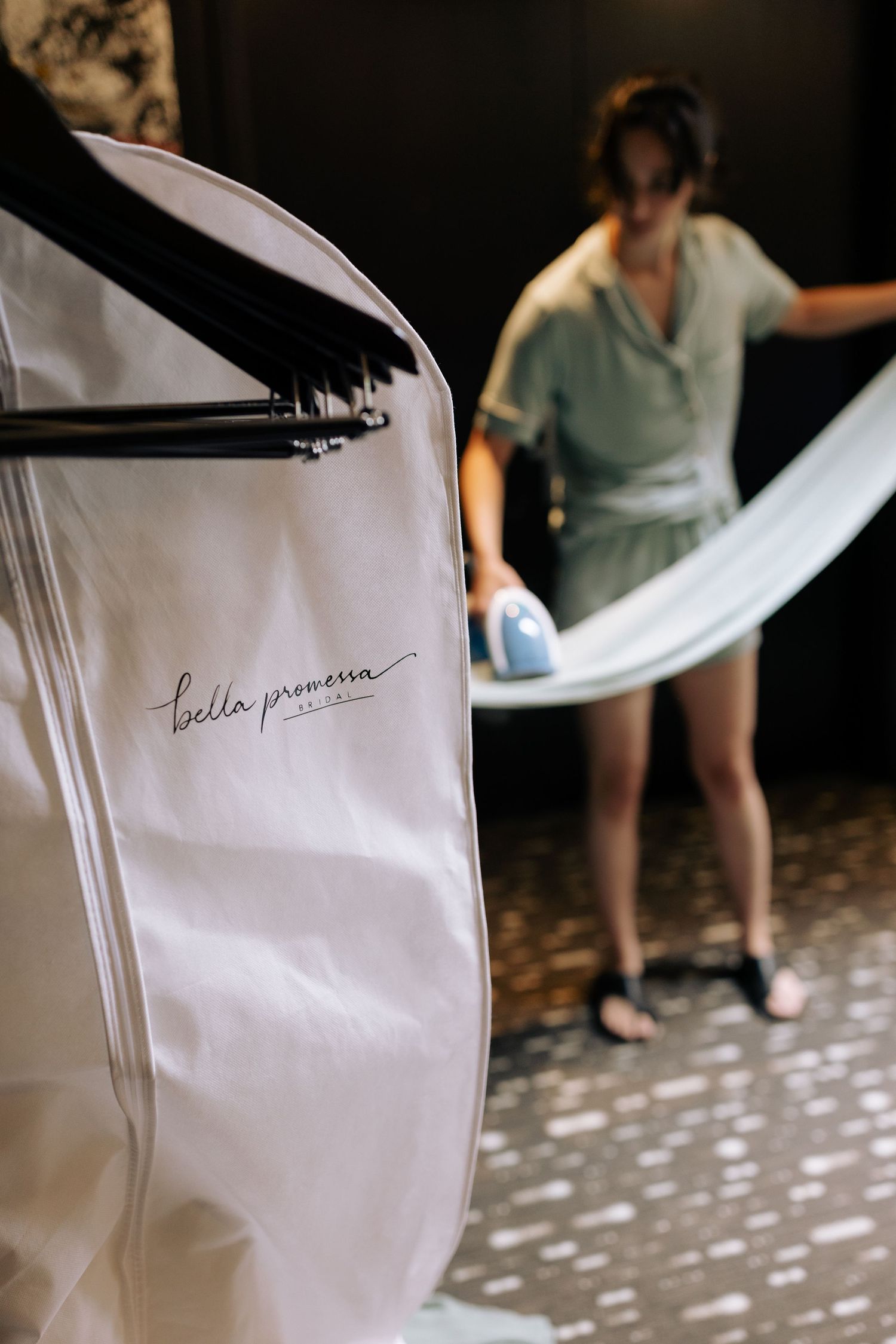 A garment bag with branding visible as someone handles fabric in the background.