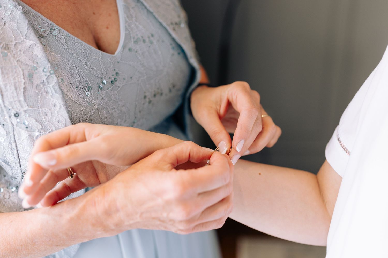 Hands adjusting wedding dress details during bridal preparation.