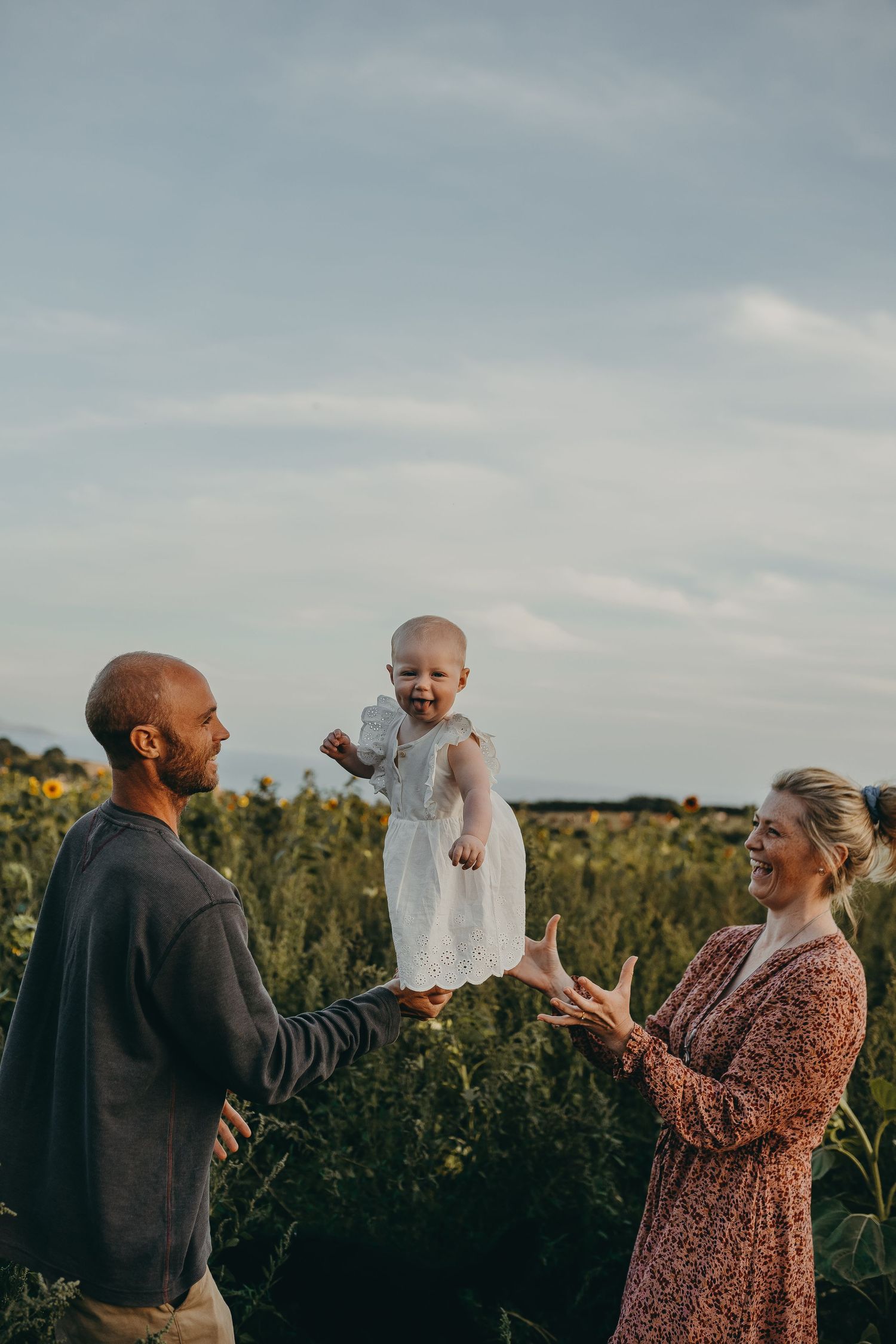 Family playing together in sunflower field during golden hour.