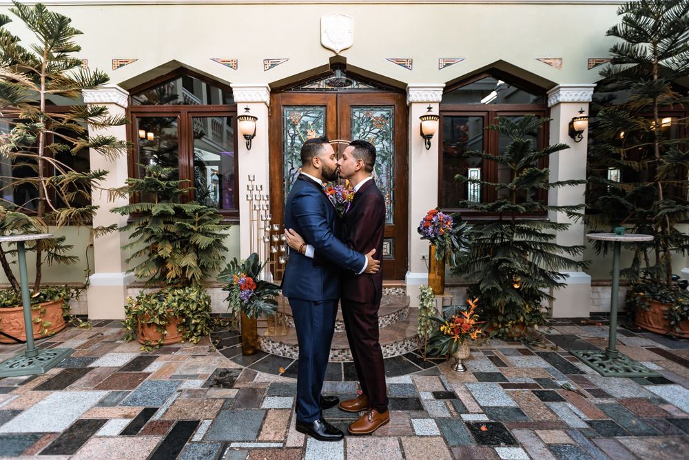 Couple sharing romantic moment in front of decorated building entrance.