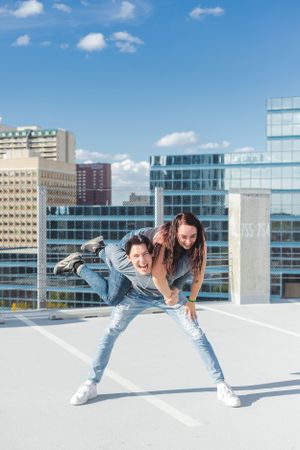 A man gives a woman a piggyback on the top of a parkade.
