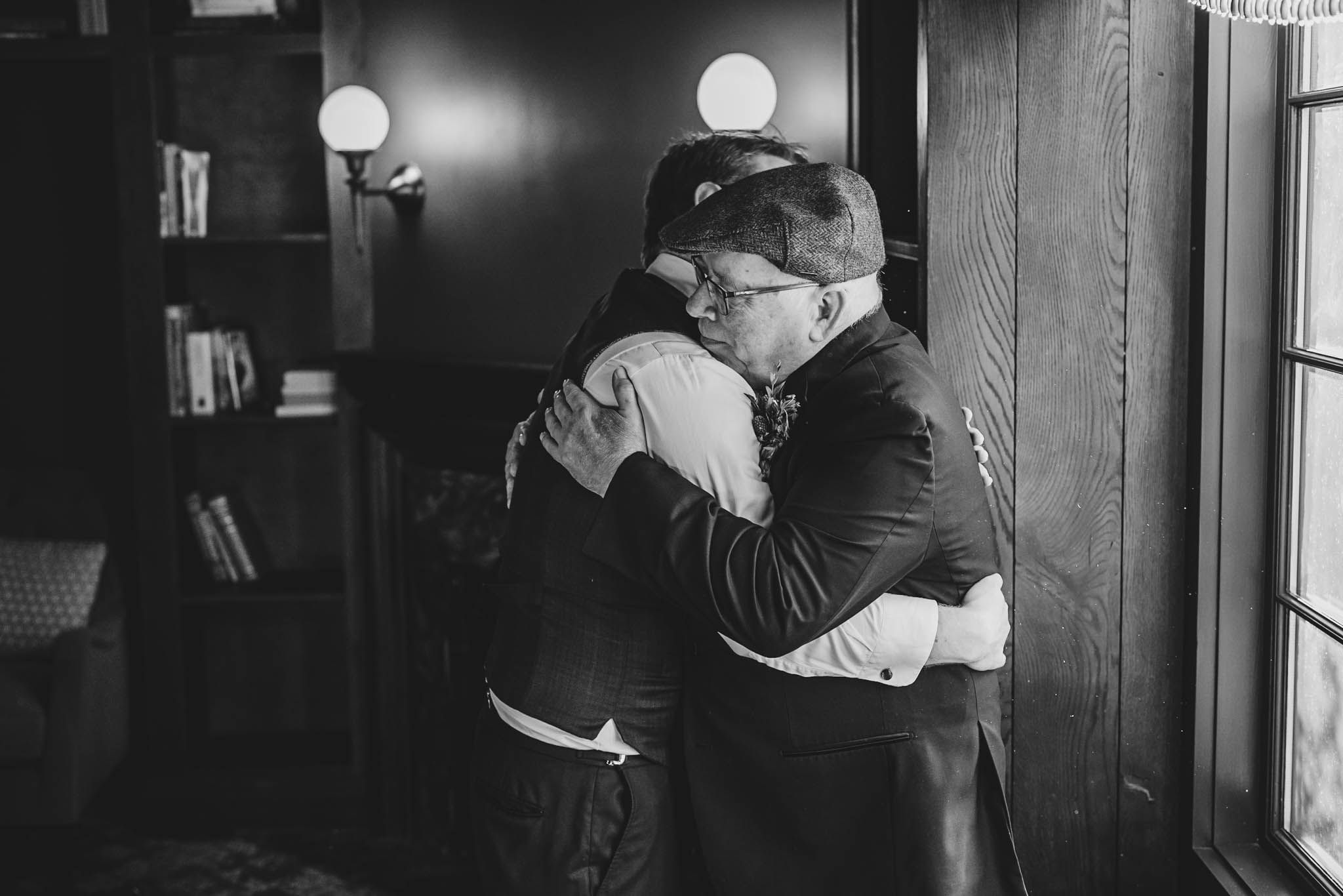 A heartfelt embrace shared in a darkened room with ambient lighting.