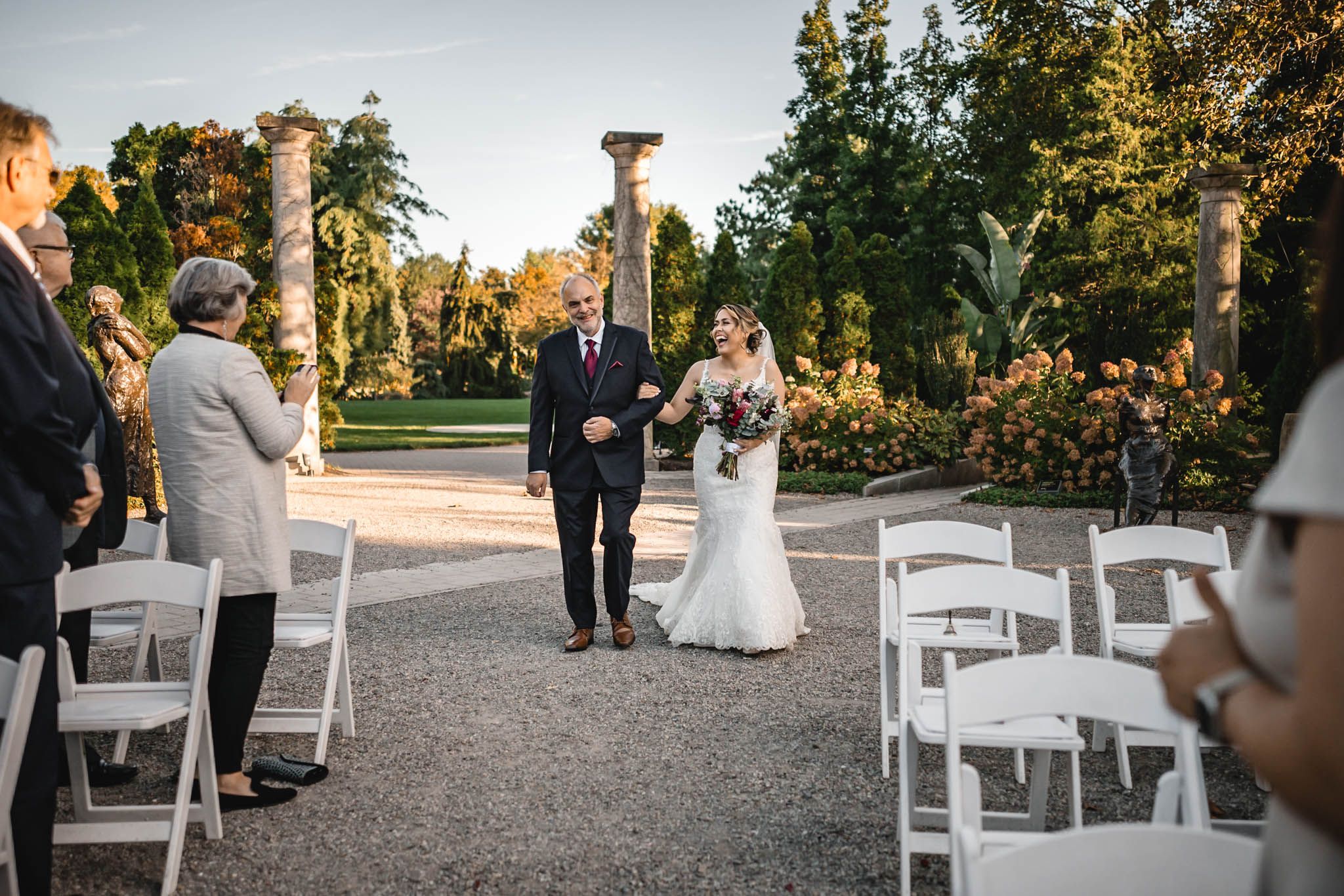 White chairs arranged on gravel path for outdoor garden wedding ceremony.