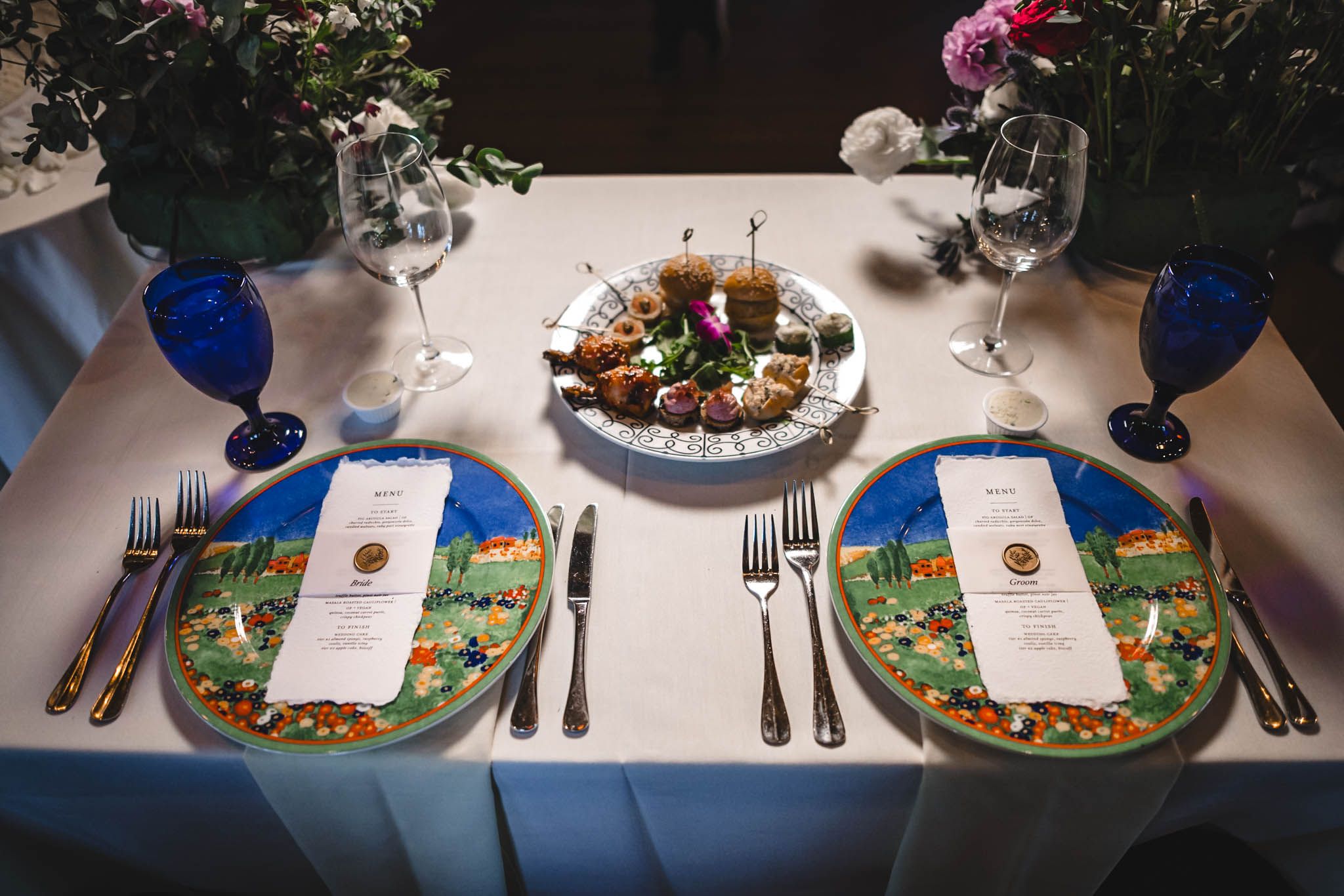 Wedding reception table settings with colorful plates and floral centerpieces.