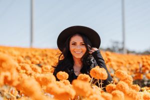 Playful portrait surrounded by bright orange marigolds in a sunny field.