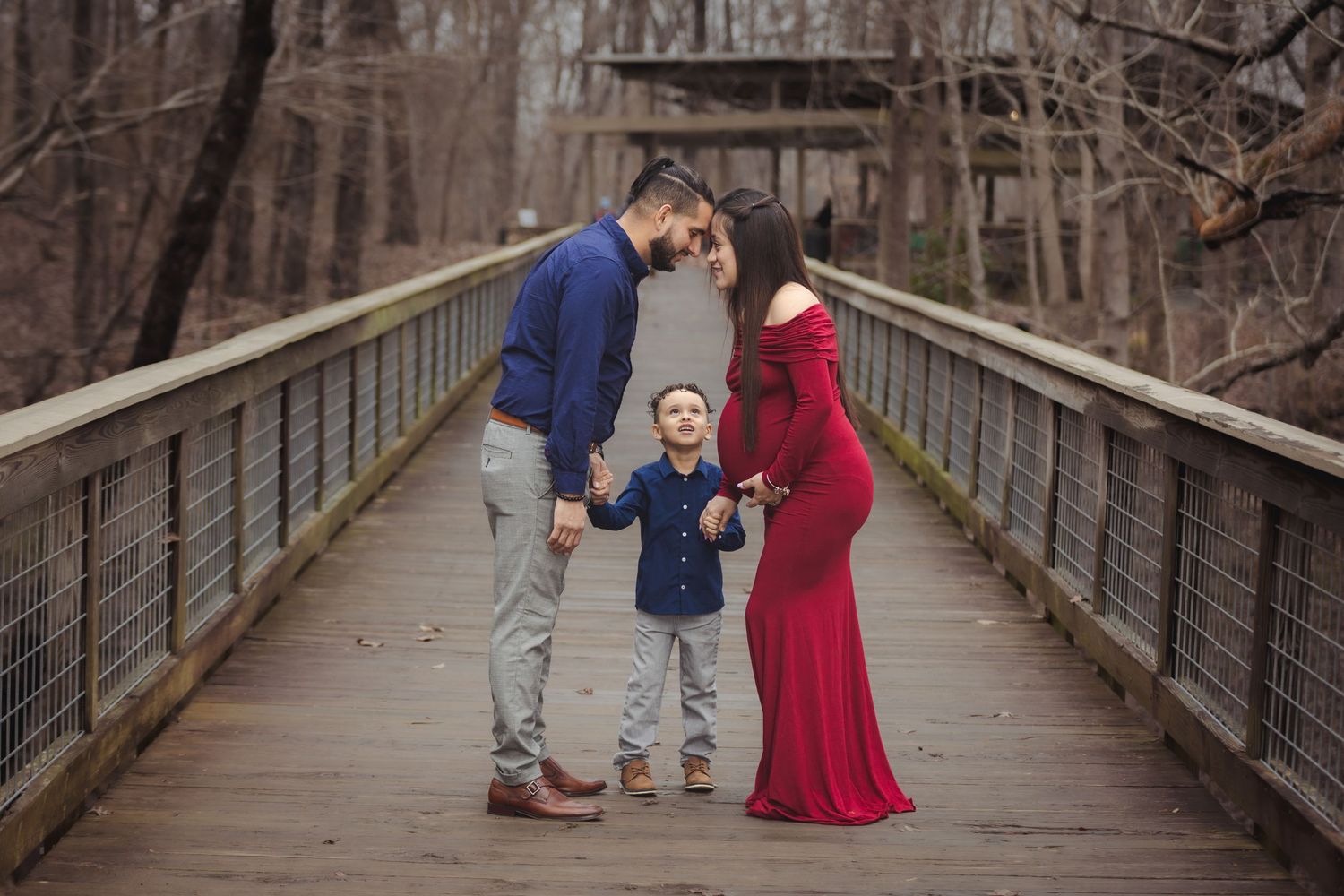 Romantic couple photoshoot on a rustic wooden bridge in winter setting.