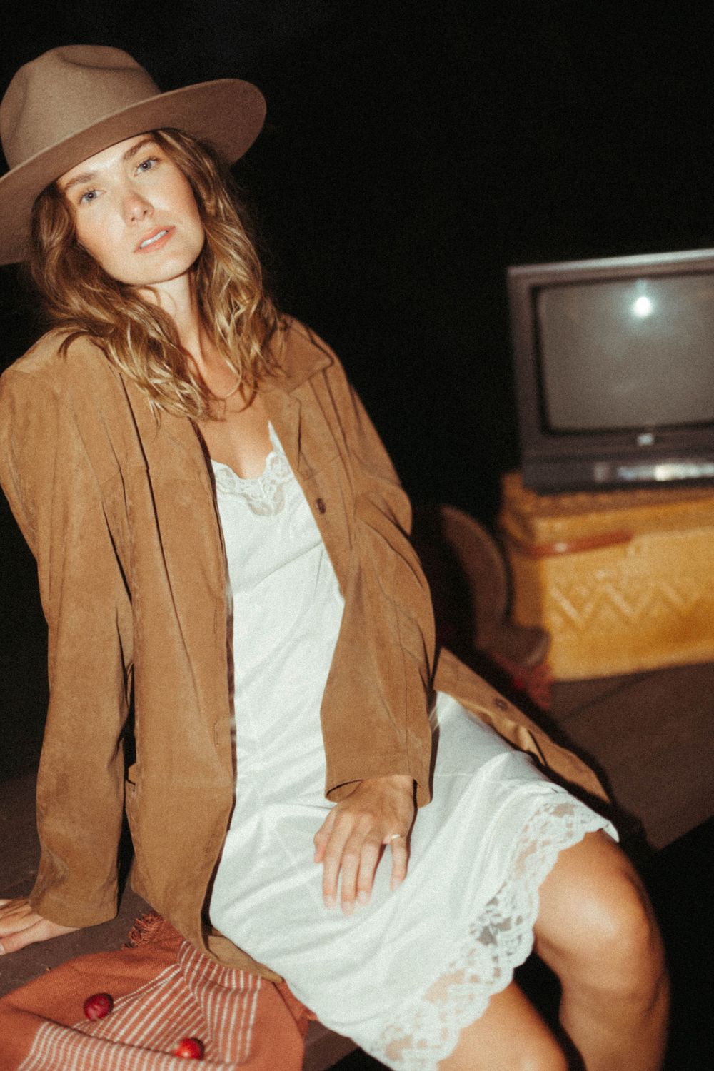 Retro-styled portrait with brown suede jacket and white dress near vintage television.