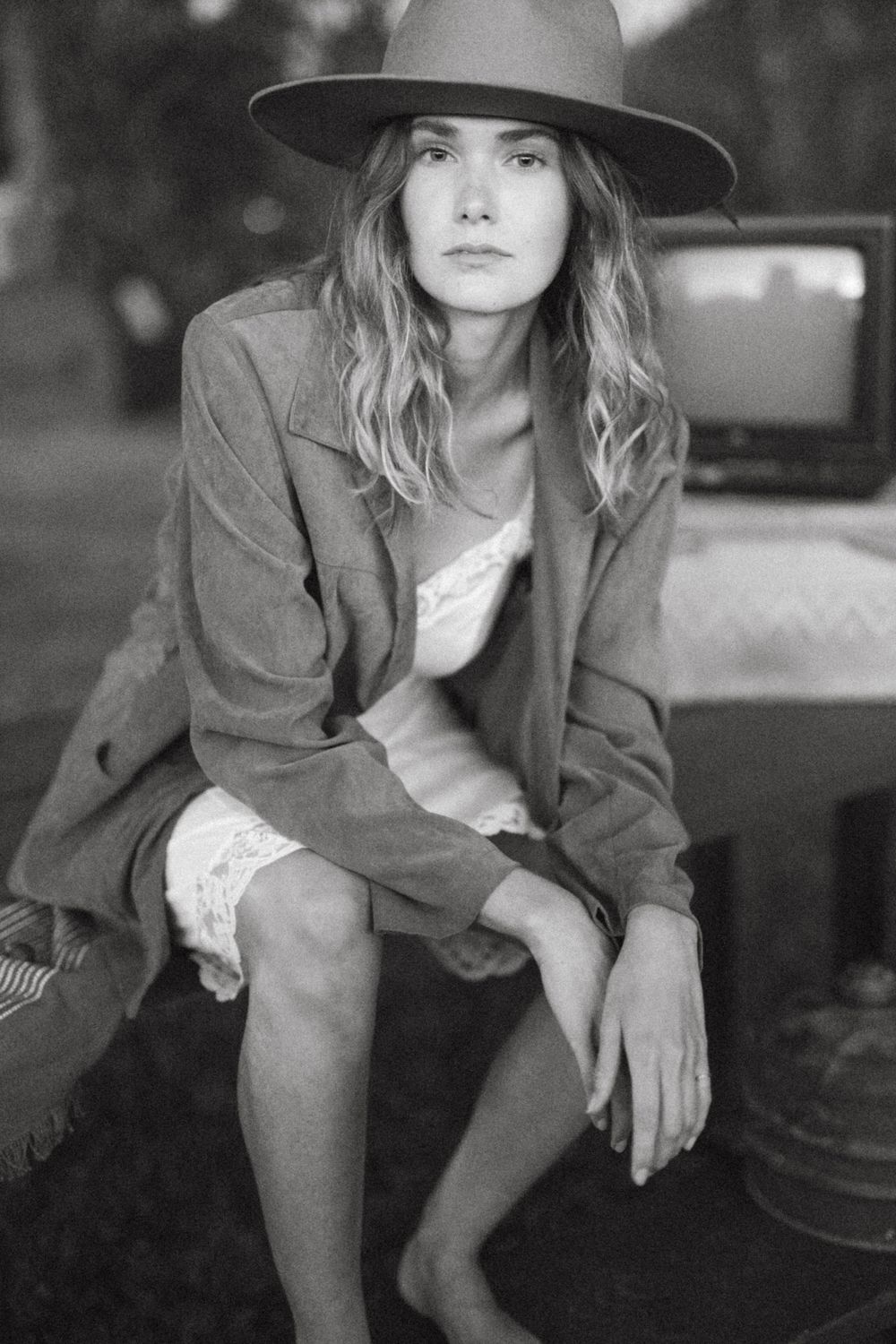 Black and white fashion portrait with wide-brimmed hat and classic blazer styling.