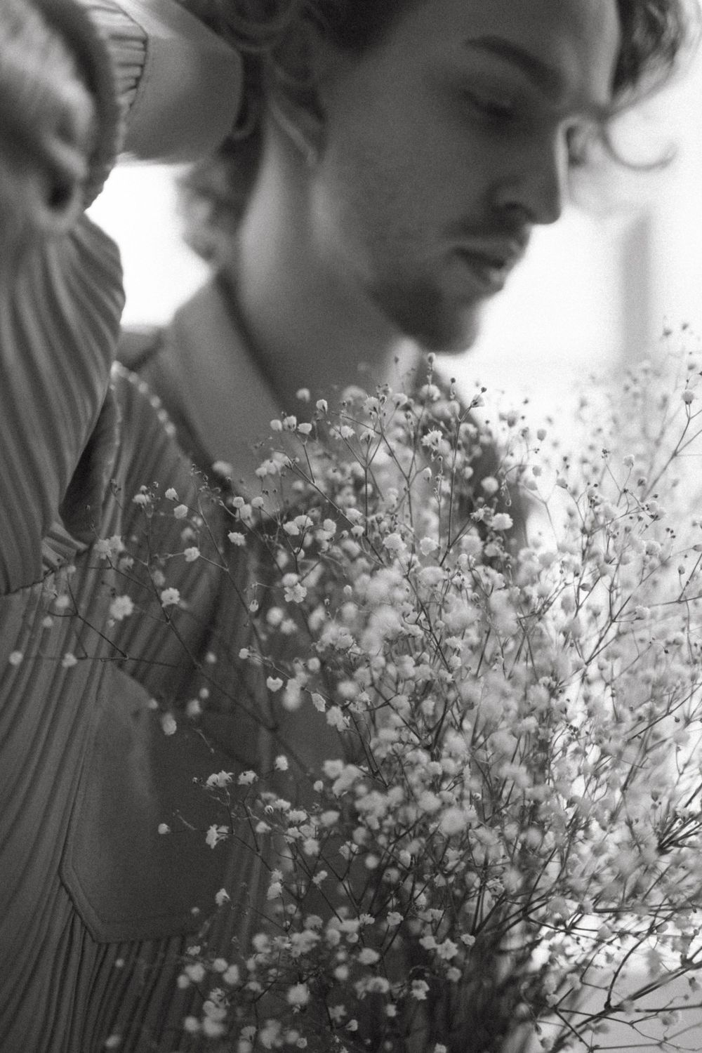 Black and white portrait showing delicate baby's breath flowers held close to the subject in soft focus.
