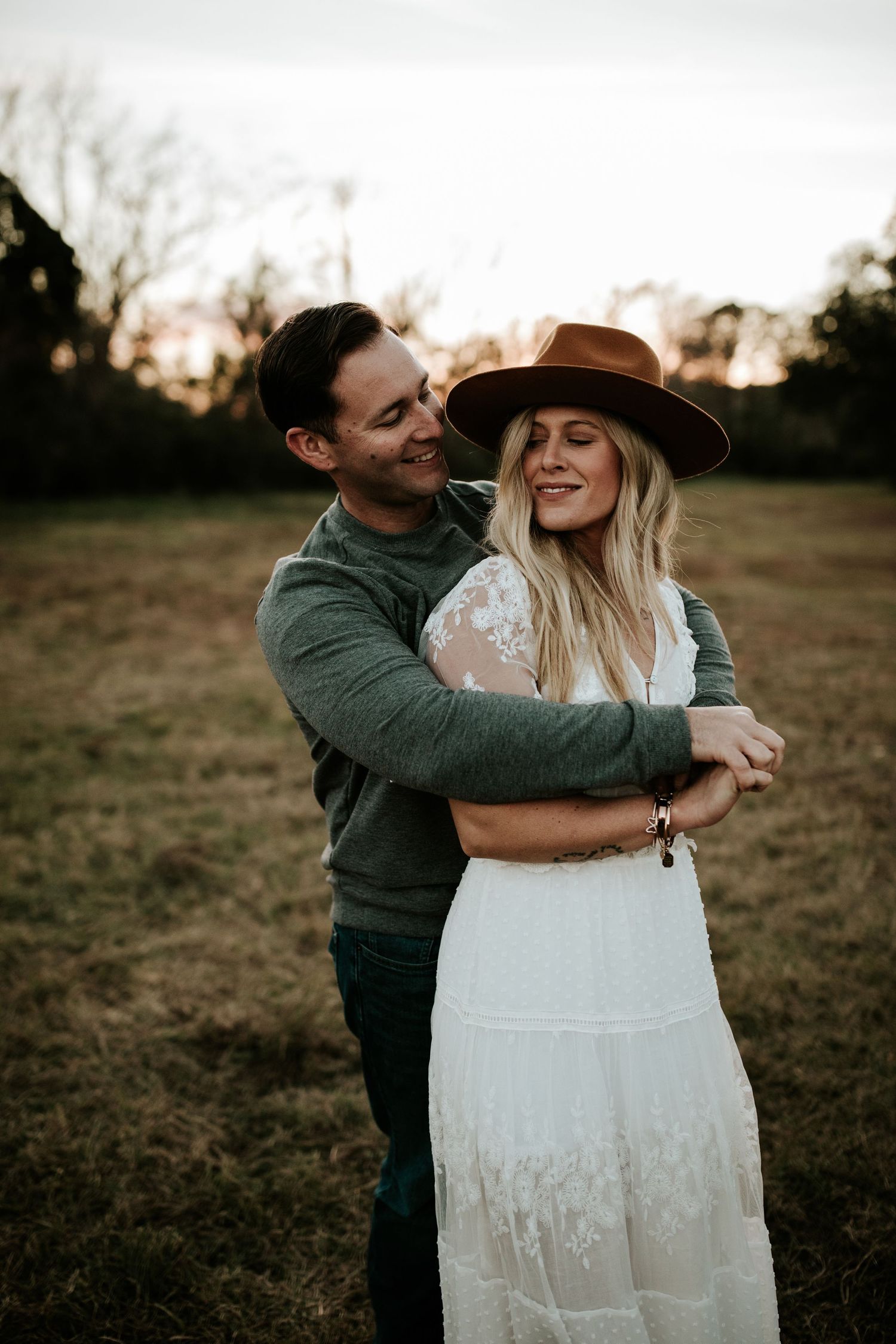 A romantic countryside photoshoot featuring a bohemian style dress and brown hat at sunset.