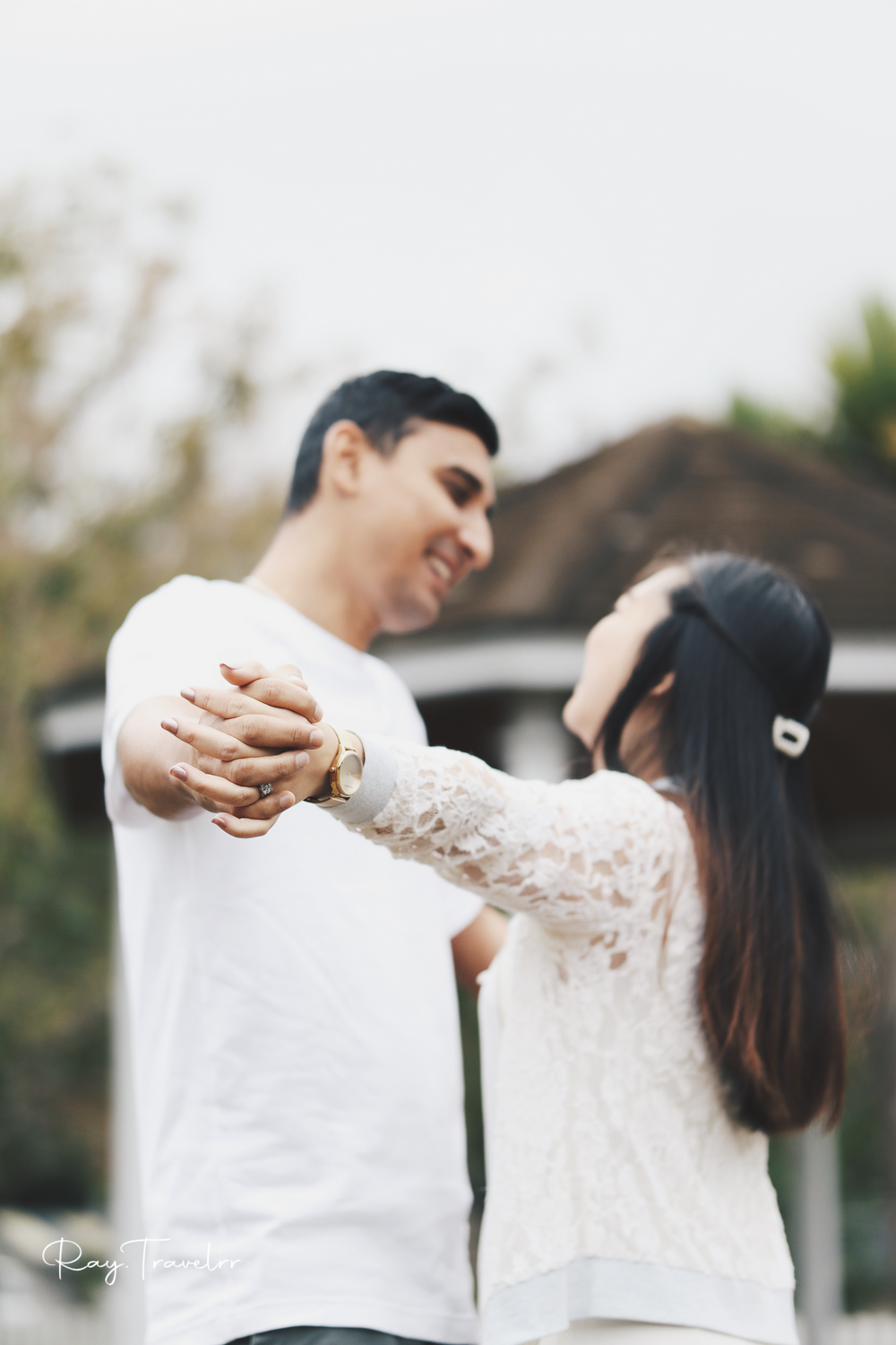 Dancing couple in white outfits share a joyful moment during their engagement photoshoot.