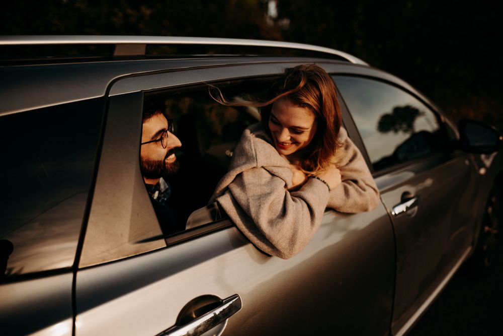 Couple sharing intimate moment through car window at dusk.