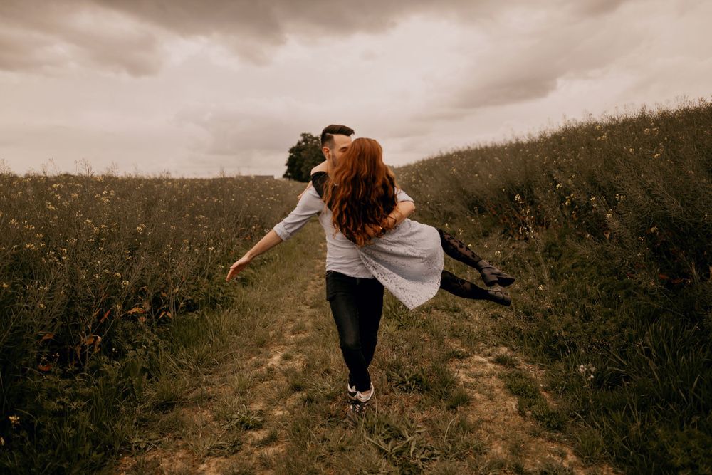 Dancing freely on a hilltop path surrounded by wildflowers and moody skies.