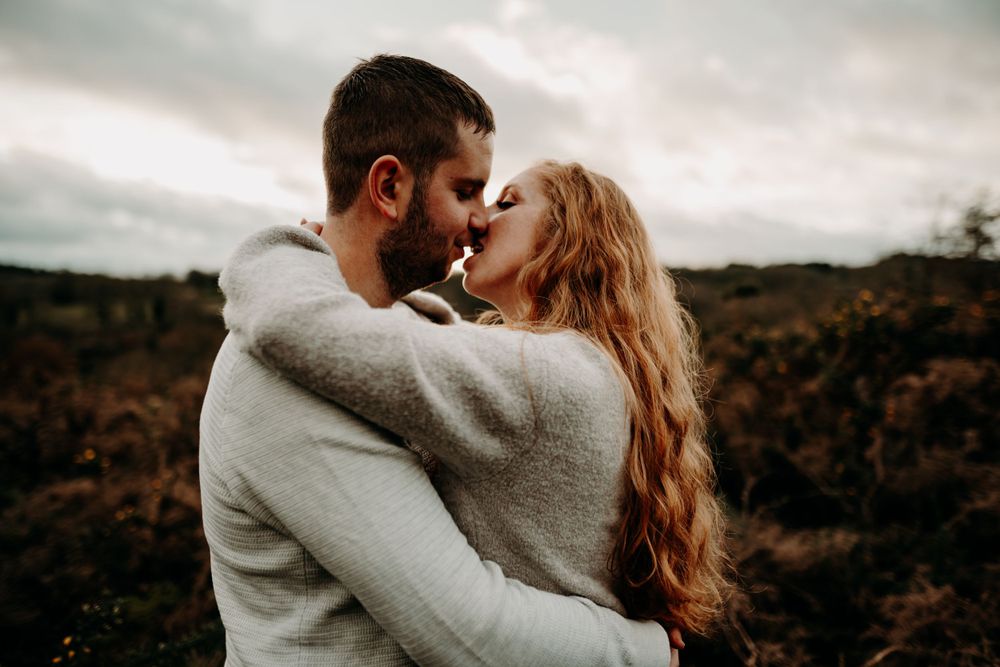 Romantic couple embraces while sharing tender moment in rural autumn setting.