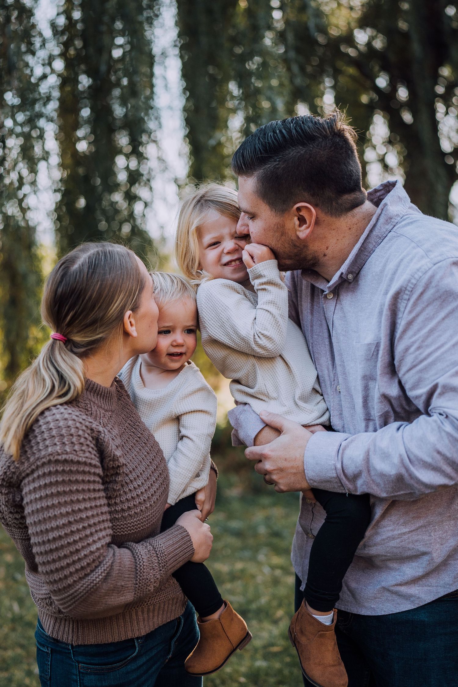 Joyful outdoor family interactions captured against a backdrop of tall trees in warm lighting.