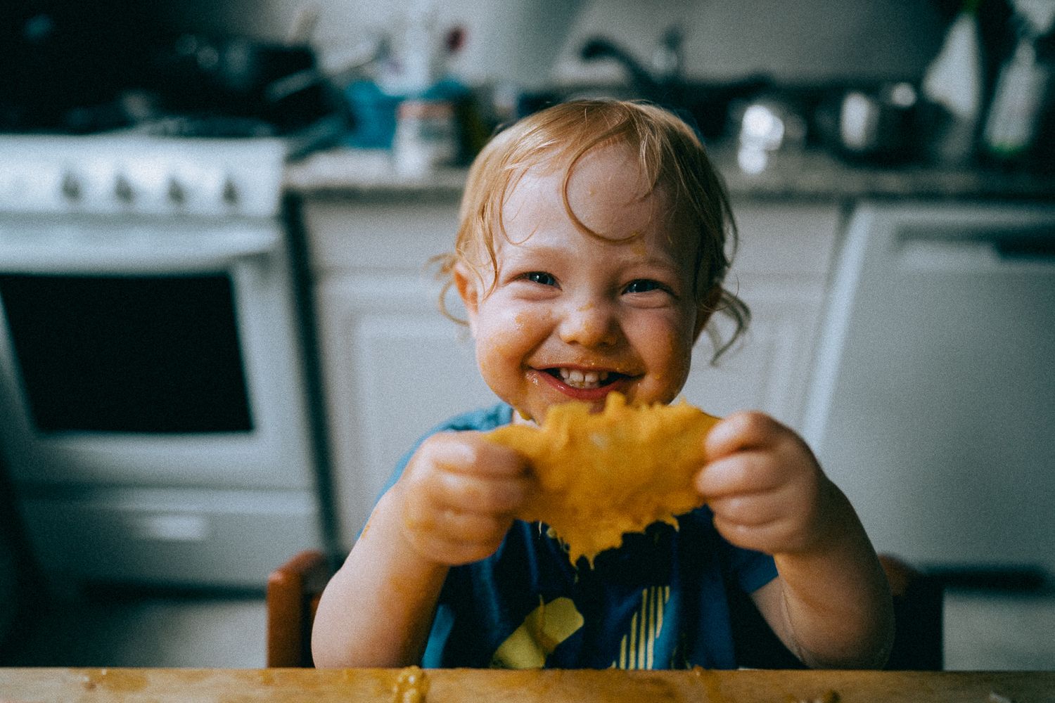 A joyful moment in the kitchen as small hands hold up a bright yellow flower with excitement.
