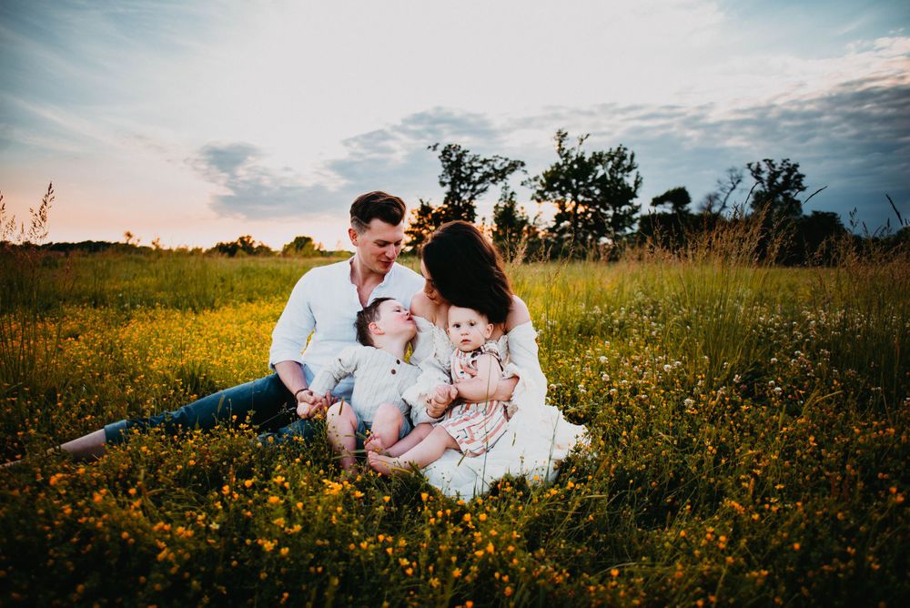 Family moment captured in blooming wildflower field during golden hour.